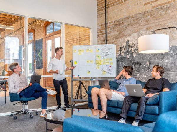 Image of a room having four people discussing content marketing, one writing the ideas on white board.