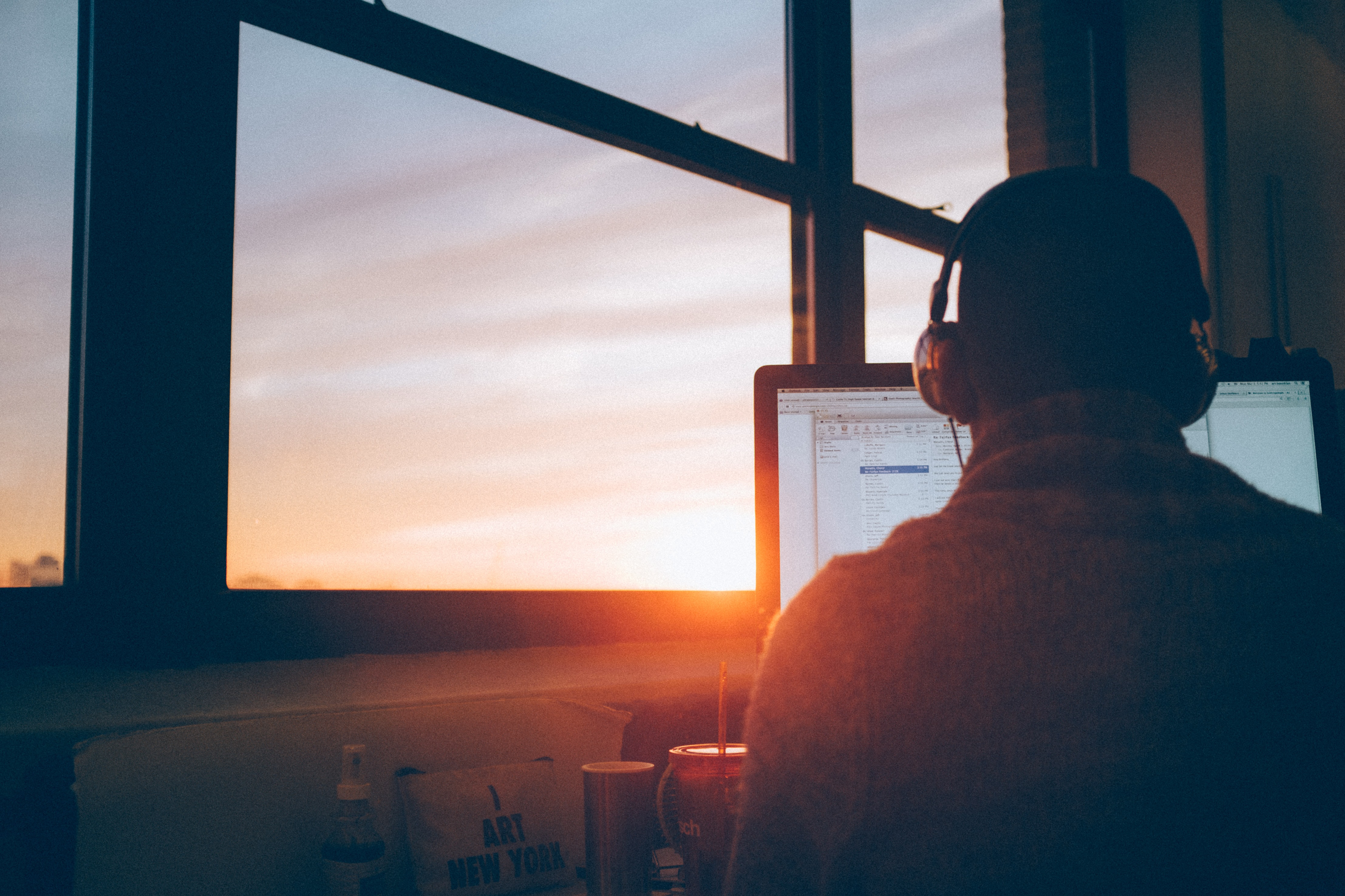 a person sitting in front of a laptop thinking with sunset in the background